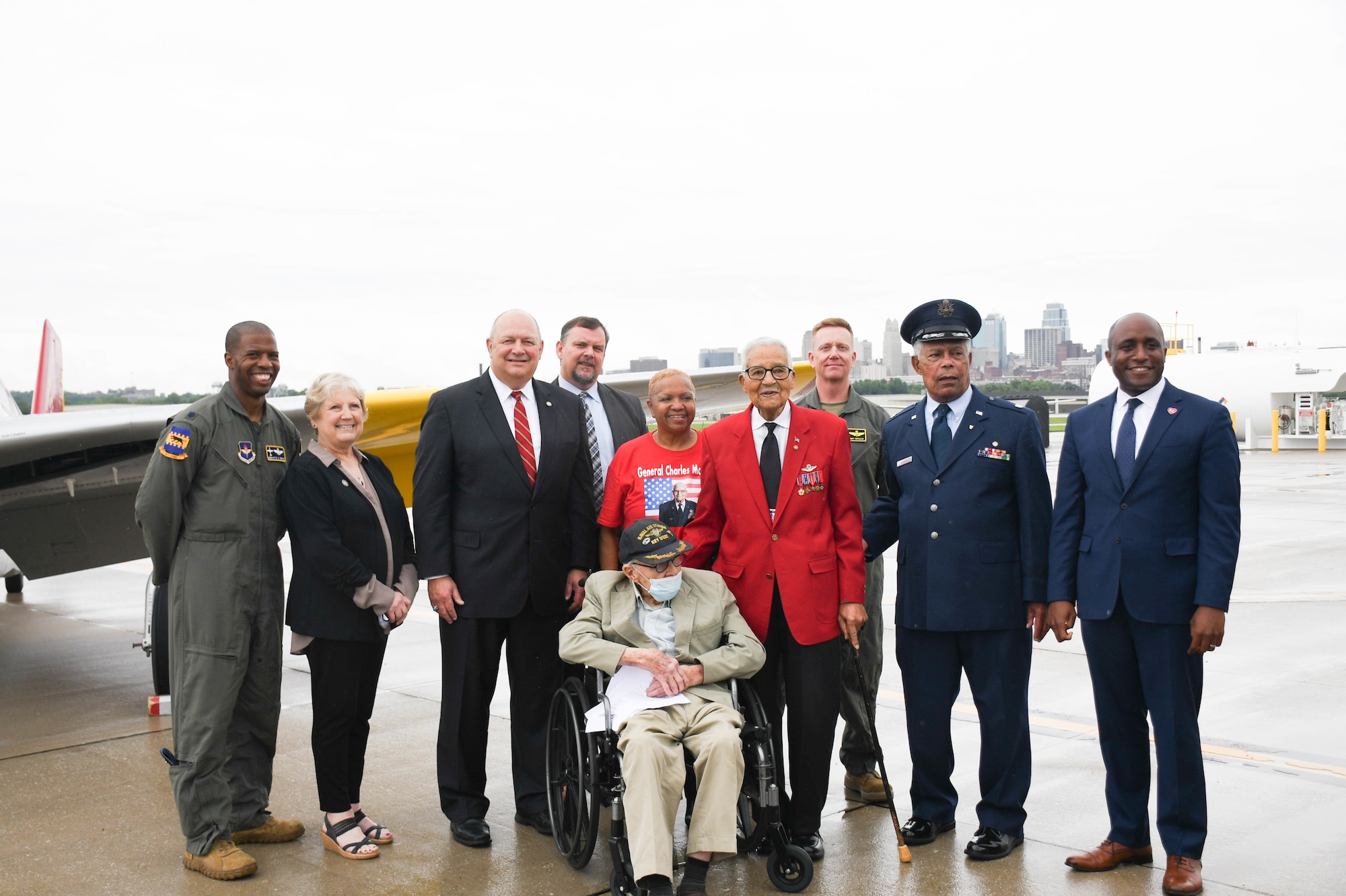 Speakers from the rededication ceremony pose for a photo near a Red-Tail P-51 Mustang painted to honor the Tuskegee Airmen