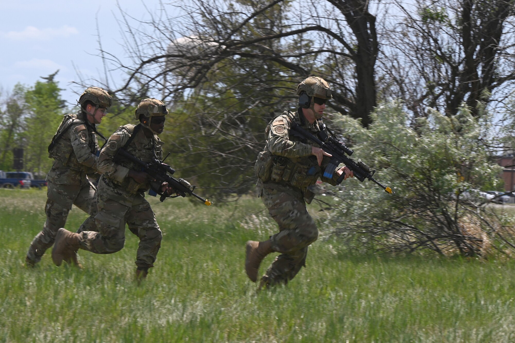Three North Dakota Air National Guard 219th Security Forces Squadron members in uniform with M4 rifles configured for training run to get into position for a training exercise at the Minot Air Force Base, N.D., June 24, 2021.