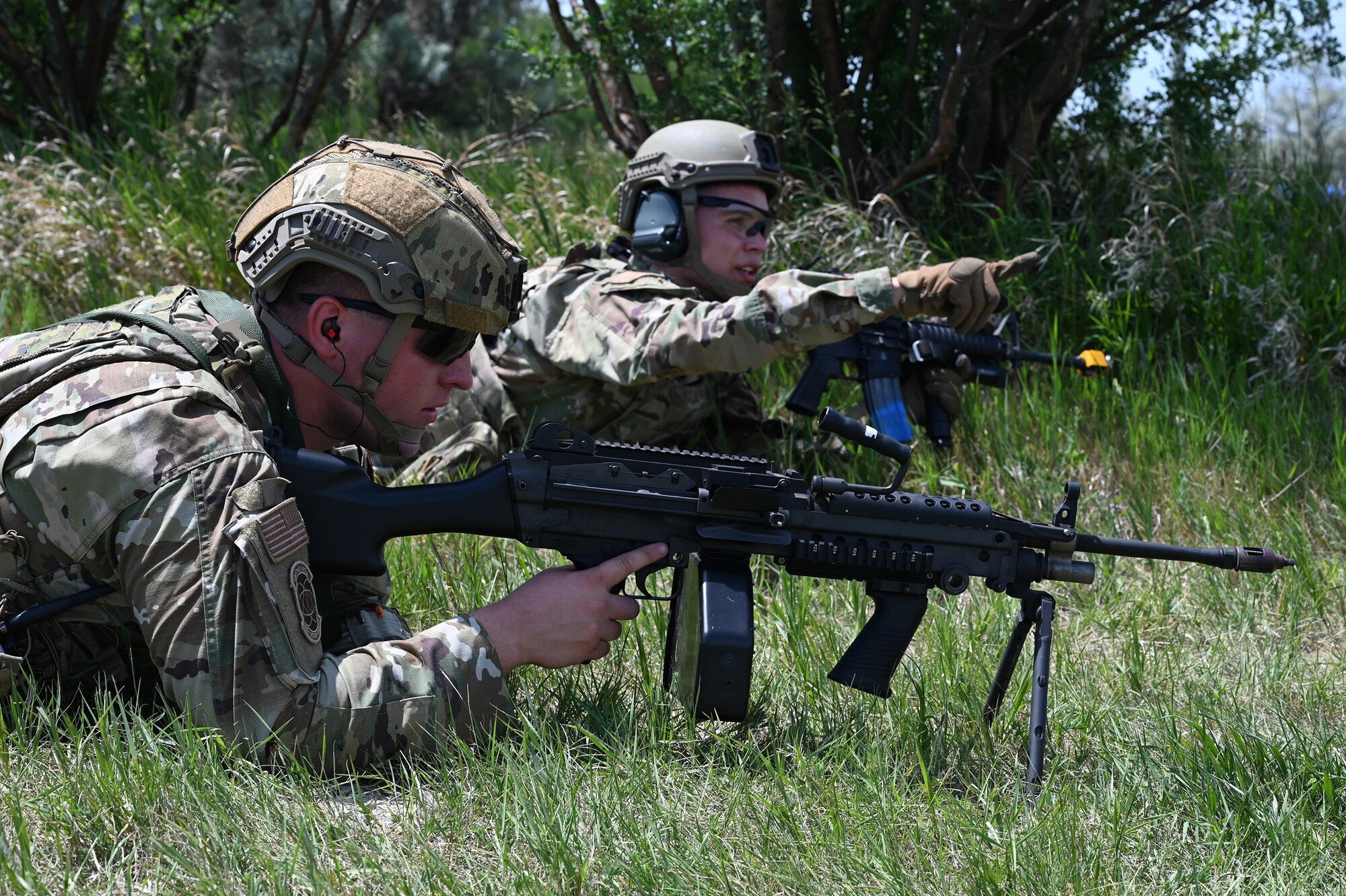 Two North Dakota Air National Guard 219th Security Forces Squadron members in military uniform with rifles modified for training lay on their stomachs during a training exercise at the Minot Air Force Base, N.D., June 24, 2021.