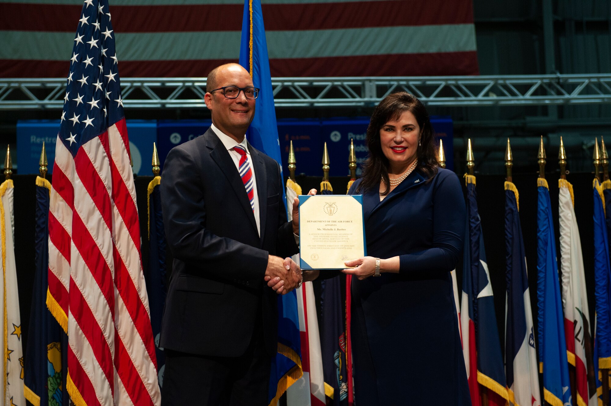 Michelle Busbee, Technical Advisor for Air and Cyberspace Intelligence at the National Air and Space Intelligence Center, receives a certificate during her promotion ceremony at the National Museum of the United States Air Force, Wright-Patterson Air Force Base, Ohio, June 30, 2021. The joint ceremony honored both Busbee and Dr. Brenner, Technical Advisor for Geospatial and Signatures Intelligence at NASIC, in their promotion to Defense Intelligence Senior Level executives.