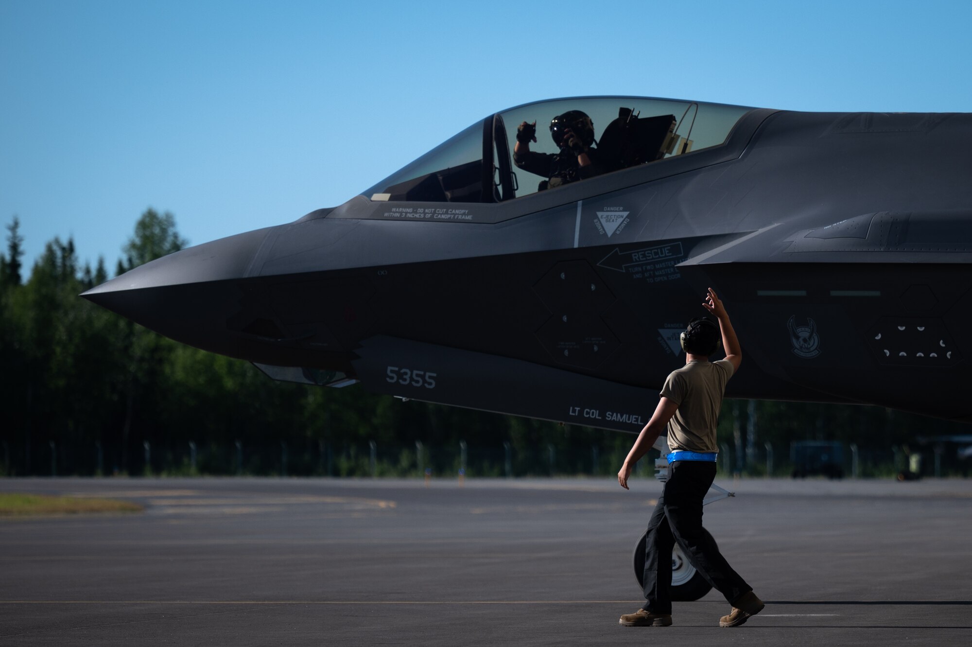 U.S. Air Force Lt. Col. Samuel Chipman, left, the 355th Fighter Squadron (FS) commander, and a crew chief assigned to the 355th Aircraft Maintenance Unit render the squadron’s salute to each other prior to takeoff on Eielson Air Force Base, Alaska, July 1, 2021.