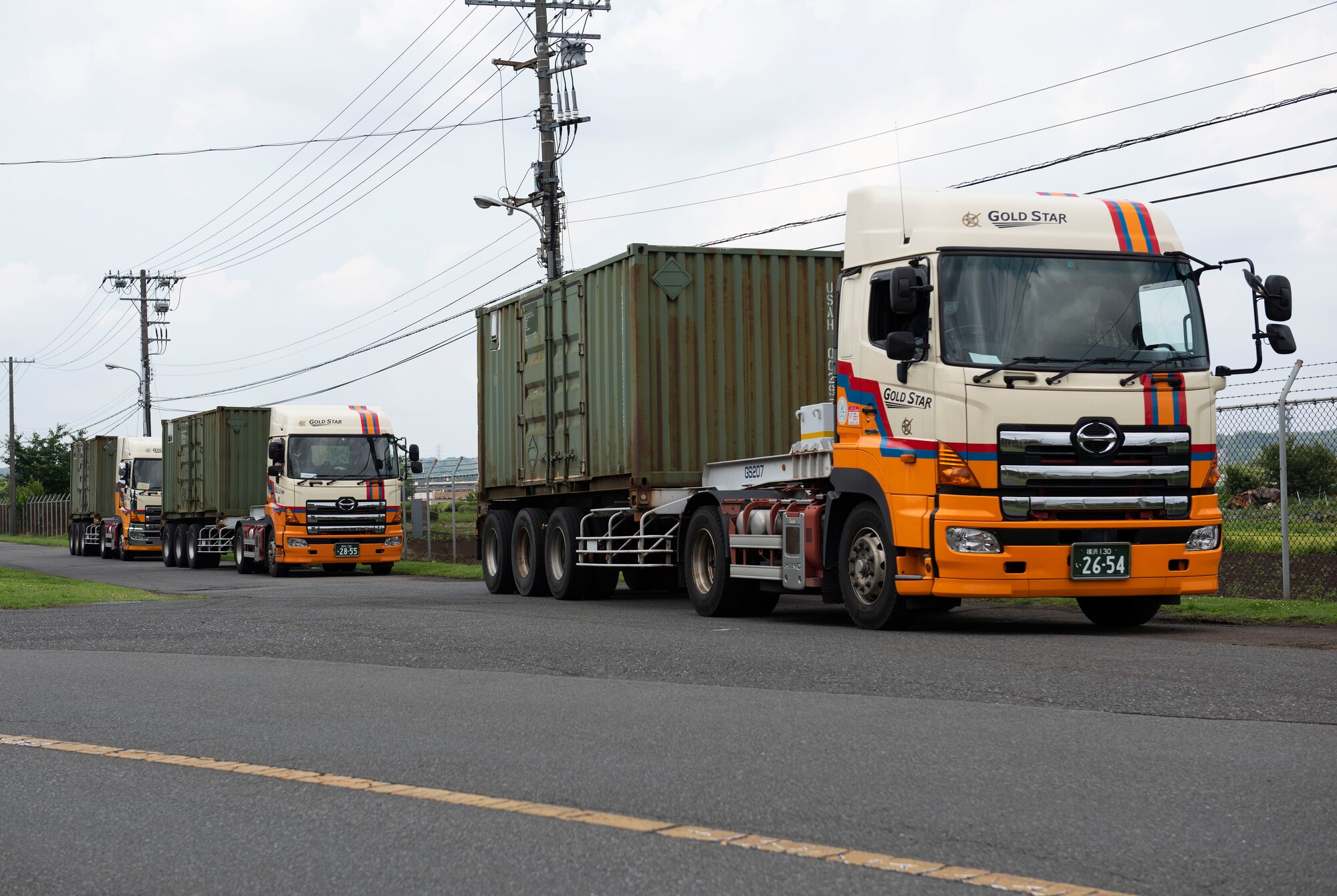 Local contractors wait to unload shipping containers for an Army field exercise at Yokota Air Base, Japan, June 24, 2021. The 311th Field Hospital from Blacklick, Ohio, spent a week building, supporting and tearing down a mock deployed hospital on Yokota. (U.S. Air Force photo by Senior Airman Hannah Bean)