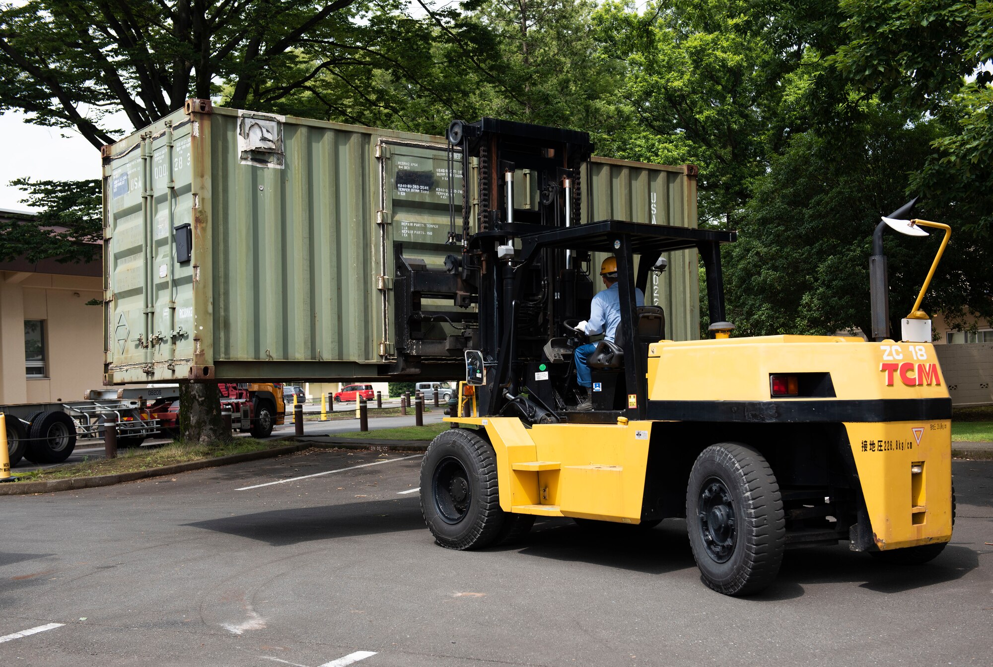 A local contractor drives a shipping container into place for an Army field exercise at Yokota Air Base, Japan, June 24, 2021. The 311th Field Hospital from Blacklick, Ohio, used the shipping containers to hold medical equipment, tents capable of supporting multiple patients and other various equipment used to run a deployed hospital. (U.S. Air Force photo by Senior Airman Hannah Bean)