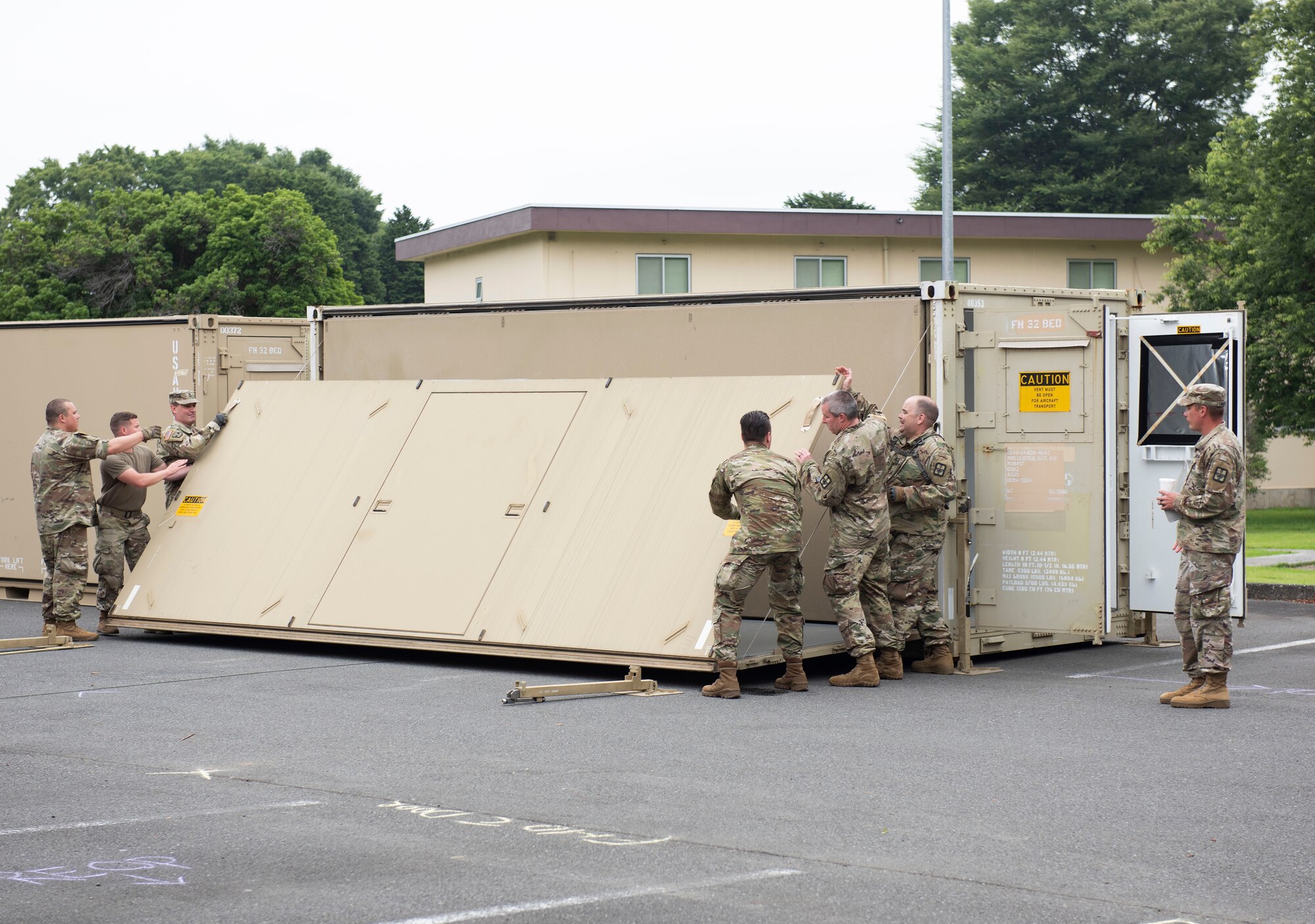 Soldiers from the 311th Field Hospital from Blacklick, Ohio, convert a container into a medical structure to build a mock deployment hospital for an Army field exercise at Yokota Air Base, Japan, June 25, 2021. When deployed the field hospital would be fully functional and come with a lab, intermediate care wards, X-ray, pharmacy and central medical supplies. (U.S. Air Force photo by Senior Airman Hannah Bean)