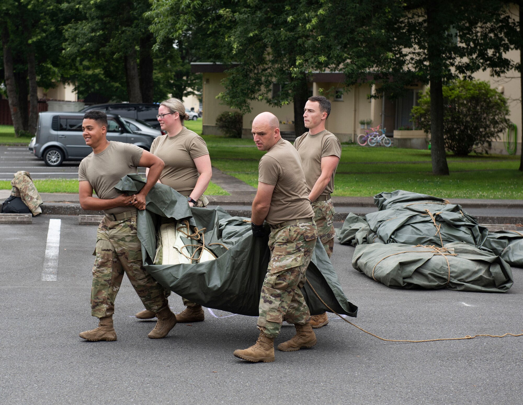 Soldiers from the 311th Field Hospital from Blacklick, Ohio, move a tent tarp to build a mock deployment hospital for an Army field exercise at Yokota Air Base, Japan, June 25, 2021. When deployed the field hospital would be fully functional and come with a lab, intermediate care wards, X-ray, pharmacy and central medical supplies. (U.S. Air Force photo by Senior Airman Hannah Bean)