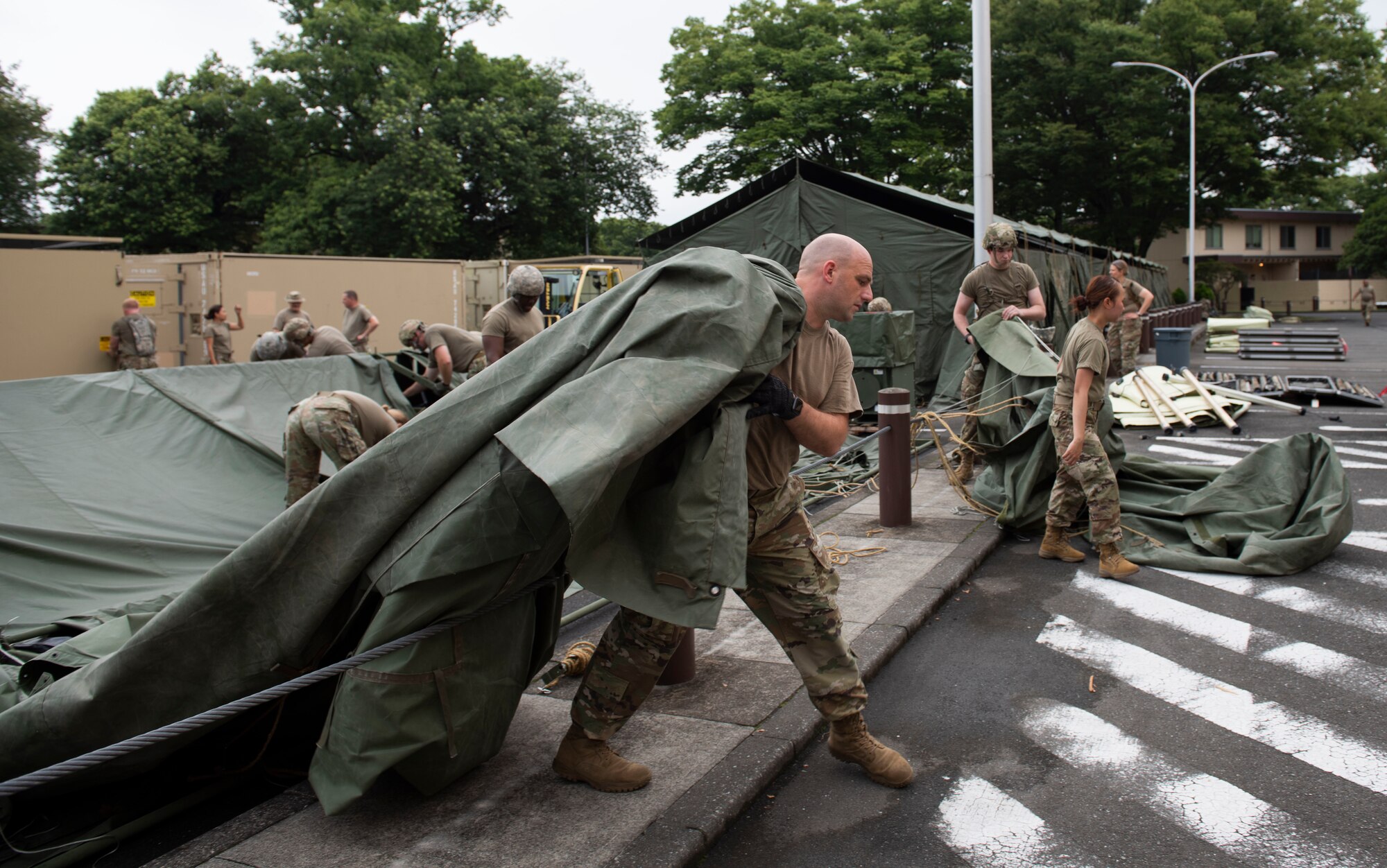 Soldiers from the 311th Field Hospital from Blacklick, Ohio, moves a tent tarp after an Army field exercise at Yokota Air Base, Japan, June 25, 2021. With the assistance of the 18th Medical Command and the 374th Airlift Wing, the 311th Field Hospital received the opportunity to mock forward deploy and practice setting up a 32-bed hospital in an unfamiliar location. (U.S. Air Force photo by Senior Airman Hannah Bean)