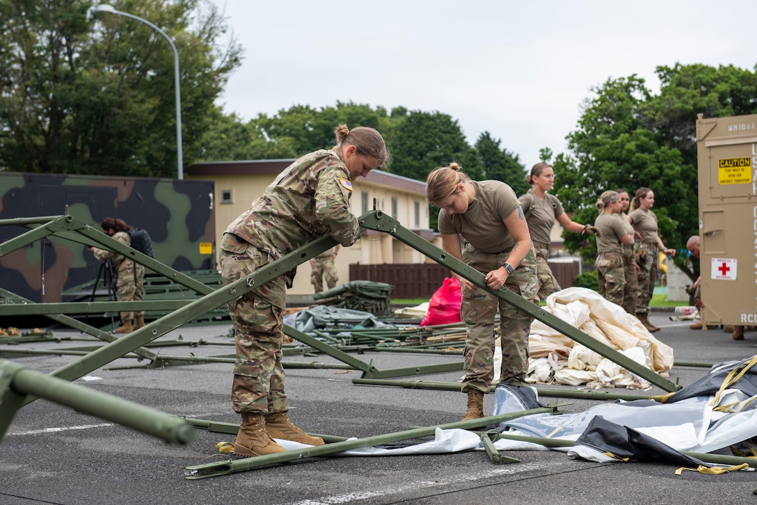 Soldiers from the 311th Field Hospital from Blacklick, Ohio, collapse tent supports after an Army field exercise at Yokota Air Base, Japan, June 25, 2021. With the assistance of the 18th Medical Command and the 374th Airlift Wing, the 311th Field Hospital received the opportunity to mock forward deploy and practice setting up a 32-bed hospital in an unfamiliar location. (U.S. Air Force photo by Senior Airman Hannah Bean)