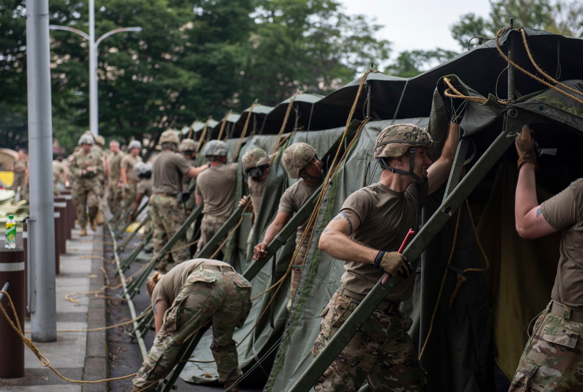 Soldiers from the 311th Field Hospital from Blacklick, Ohio, prepare to lower a tent after an Army field exercise at Yokota Air Base, Japan, June 25, 2021. With the assistance of the 18th Medical Command and the 374th Airlift Wing, the 311th Field Hospital received the opportunity to mock forward deploy and practice setting up a 32-bed hospital in an unfamiliar location. (U.S. Air Force photo by Senior Airman Hannah Bean)