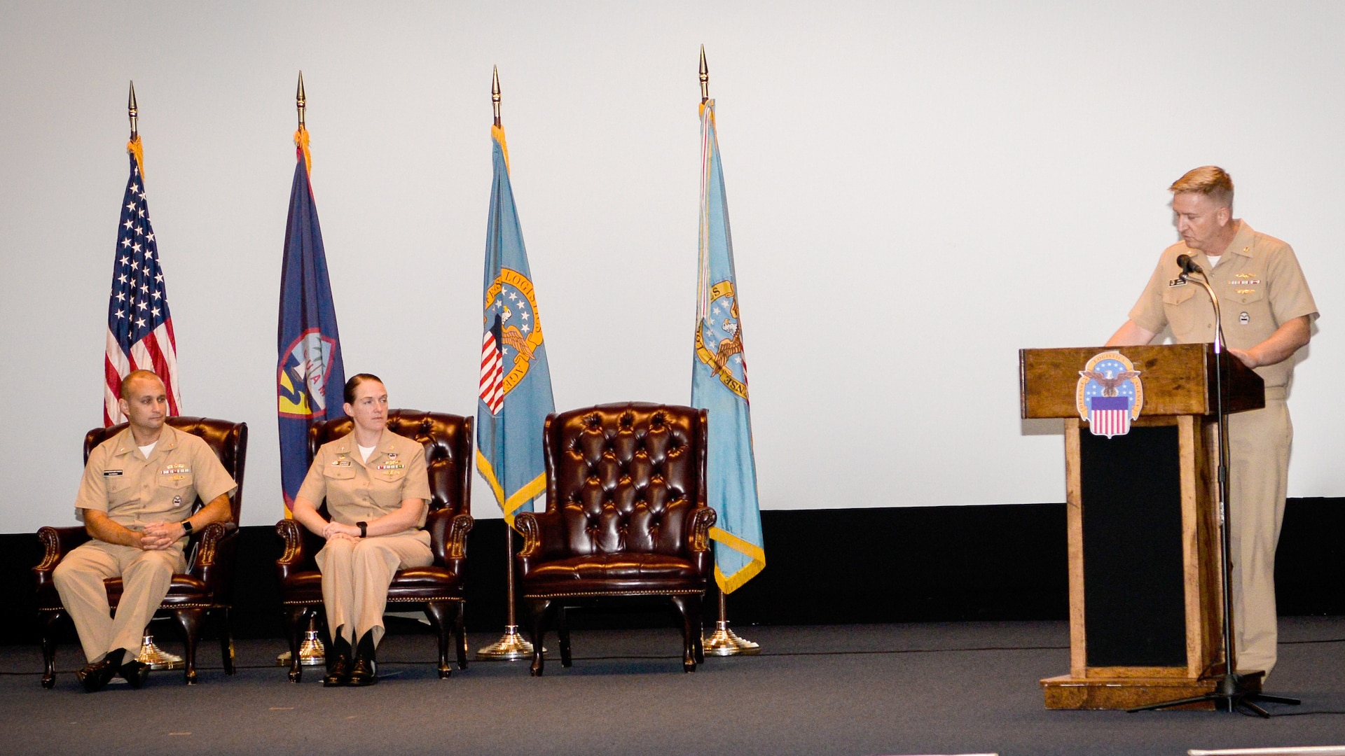 Three Navy officers on a stage