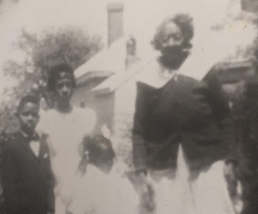 A boy, two girls and a woman pose for a photo in front of a house.