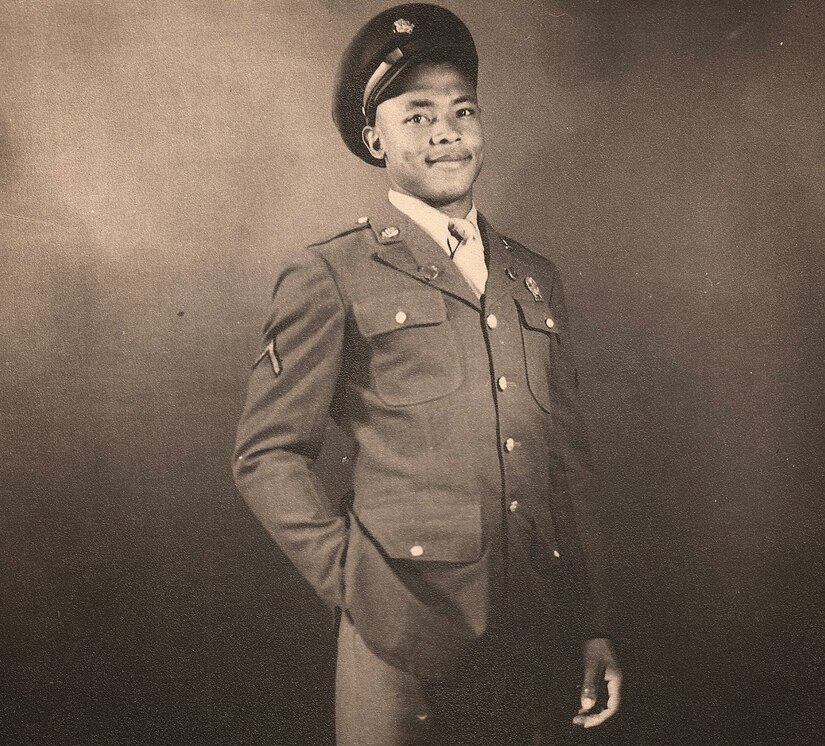 A man in a uniform and cap poses for a photo with one hand in his pocket.