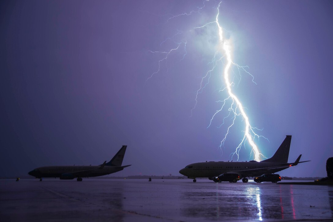Lighting strikes behind two parked aircraft.