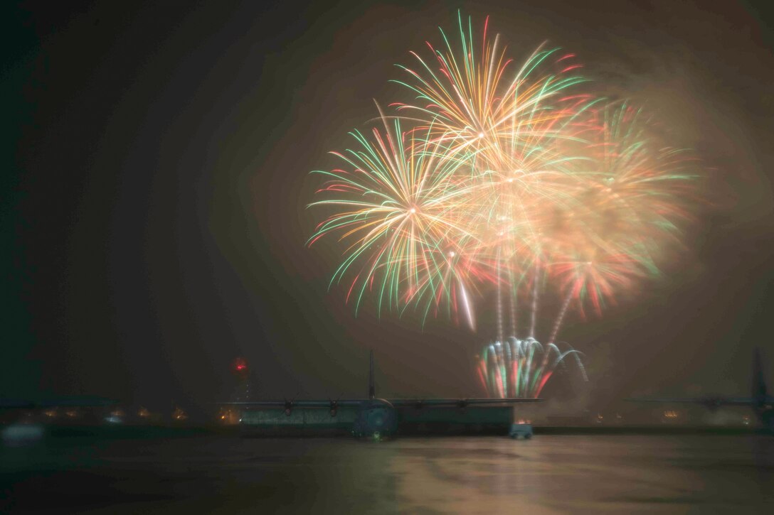Fireworks explode behind an aircraft.