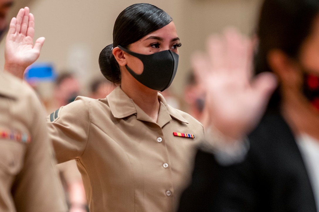 A Marine holds up her right hand during a ceremony.