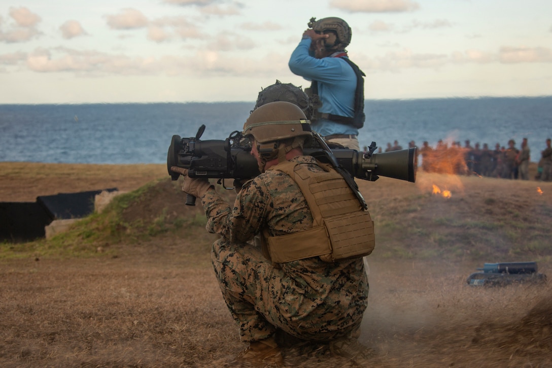 A Marine aims a weapon in a field.
