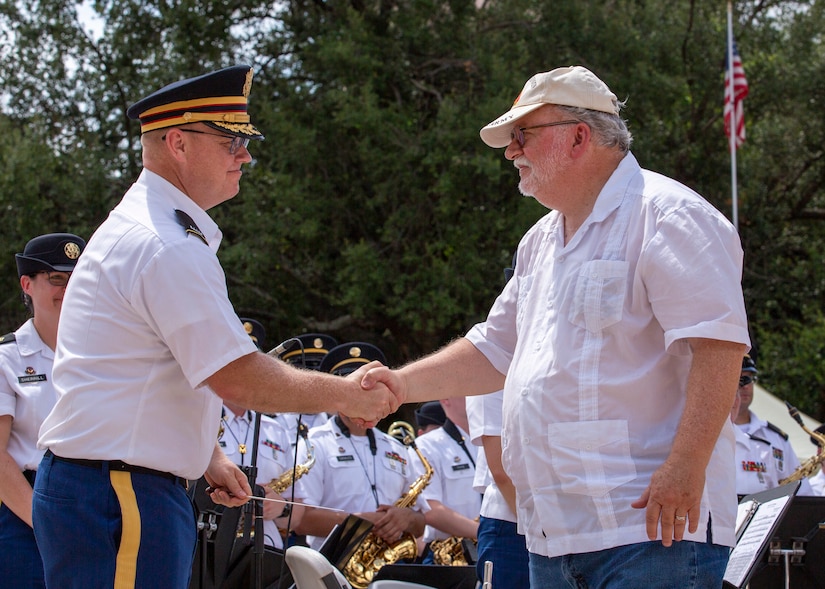 Chief Warrant Officer 4 Jared DeLaney, commander and bandmaster of “Fort Sam’s Own” 323d Army Band, left, shakes hands with Retired U.S. Army Chief Warrant Officer 4 Charles Booker, bandmaster for 5th Army Band from 1972-1976, during an Independence Day concert held at The Alamo, July 2, 2021. Booker was spontaneously asked to lead the concert during the last song, “Stars and Stripes Forever.” The 323d performed with the 313th Army Band, a U.S. Army Reserve band from Redstone Arsenal in Huntsville, Alabama. (U.S. Army Photo by Bethany Huff).