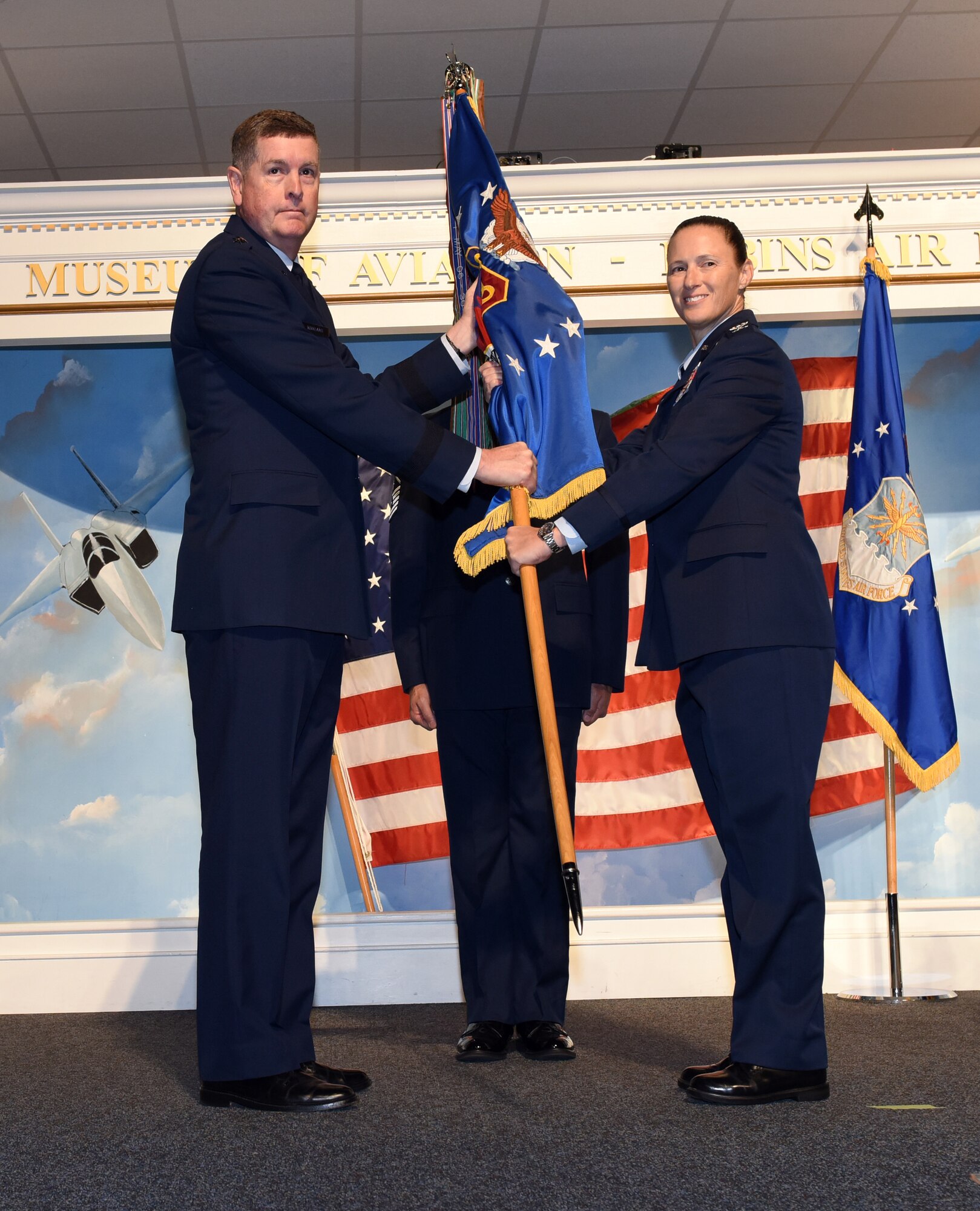 Photo shows two people passing a flag.