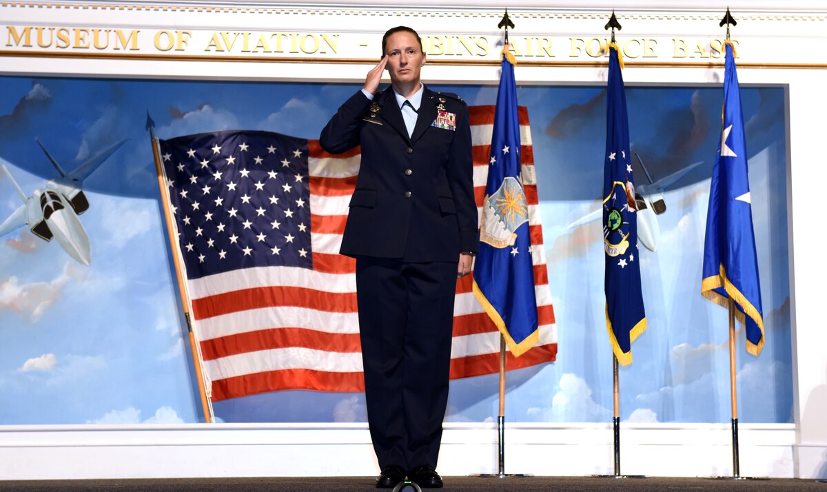 Photo shows Col. Droz standing on stage rendering a salute.