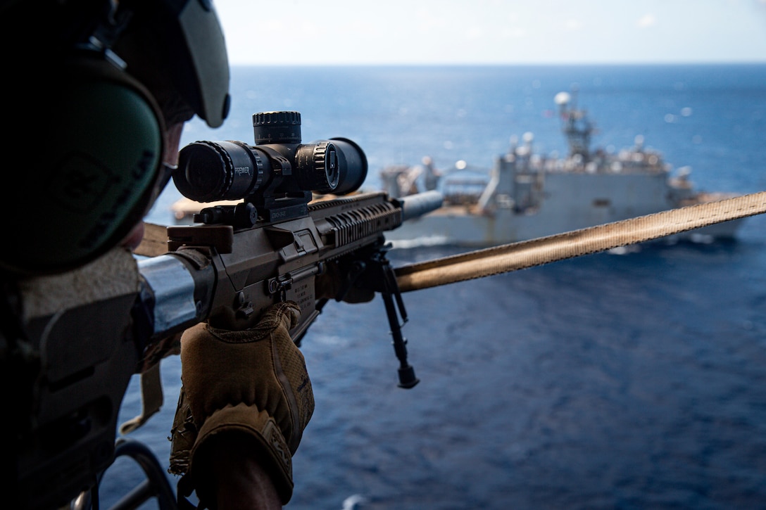 A U.S. Marine with Force Reconnaissance Platoon, 31st Marine Expeditionary Unit, sights into his M1110 semi-automatic sniper system to provide security during a Maritime Interdiction Operation training exercise aboard the USS Germantown in the Philippine Sea, June 24, 2021. The MIO consisted of Force Reconnaissance Marines fast roping on to the USS Germantown and executing a search and seizure scenario with support from the Battalion Landing Team 3/5 as the security element. The 31st MEU is operating aboard ships of the America Amphibious Ready Group in the 7th fleet area of operation to enhance interoperability with allies and partners and serve as a ready response force to defend peace and stability in the Indo-Pacific region.