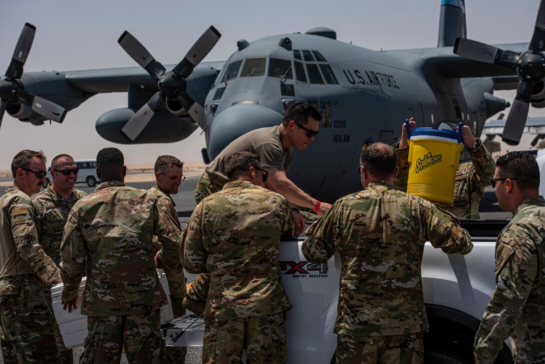 Members of the 386th Air Expeditionary Wing grab coolers of ice water from the back of a truck for a “fini flight” celebration on the flight line at Ali Al Salem Air Base, Kuwait, July 4, 2021.