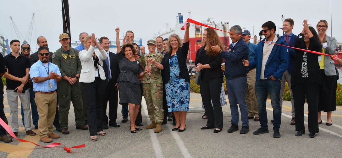 Col. Julie Balten, commander of the U.S. Army Corps of Engineers Los Angeles District, center, along with Oxnard Harbor District Commissioner Celina Zacarias, left, and Oxnard Harbor District Vice President Mary Anne Rooney, right, as well as several others celebrate after cutting the ribbon during a ceremony for the completion of the deepening of Port Hueneme Harbor June 28 at Port Hueneme, California. Also pictured are members of the Port of Hueneme/Oxnard Harbor District, U.S. Army Corps of Engineers, Curtin Maritime, KPFF, Naval Base Ventura County, City of Port Hueneme and representatives from Congresswoman Julia Brownley’s office and Assembly Member Jacqui Irwin’s office. 
The deepening of the harbor from 35 to 40 feet will enable the port to accommodate larger vessels, which support not only the nation’s economy, but also national defense.