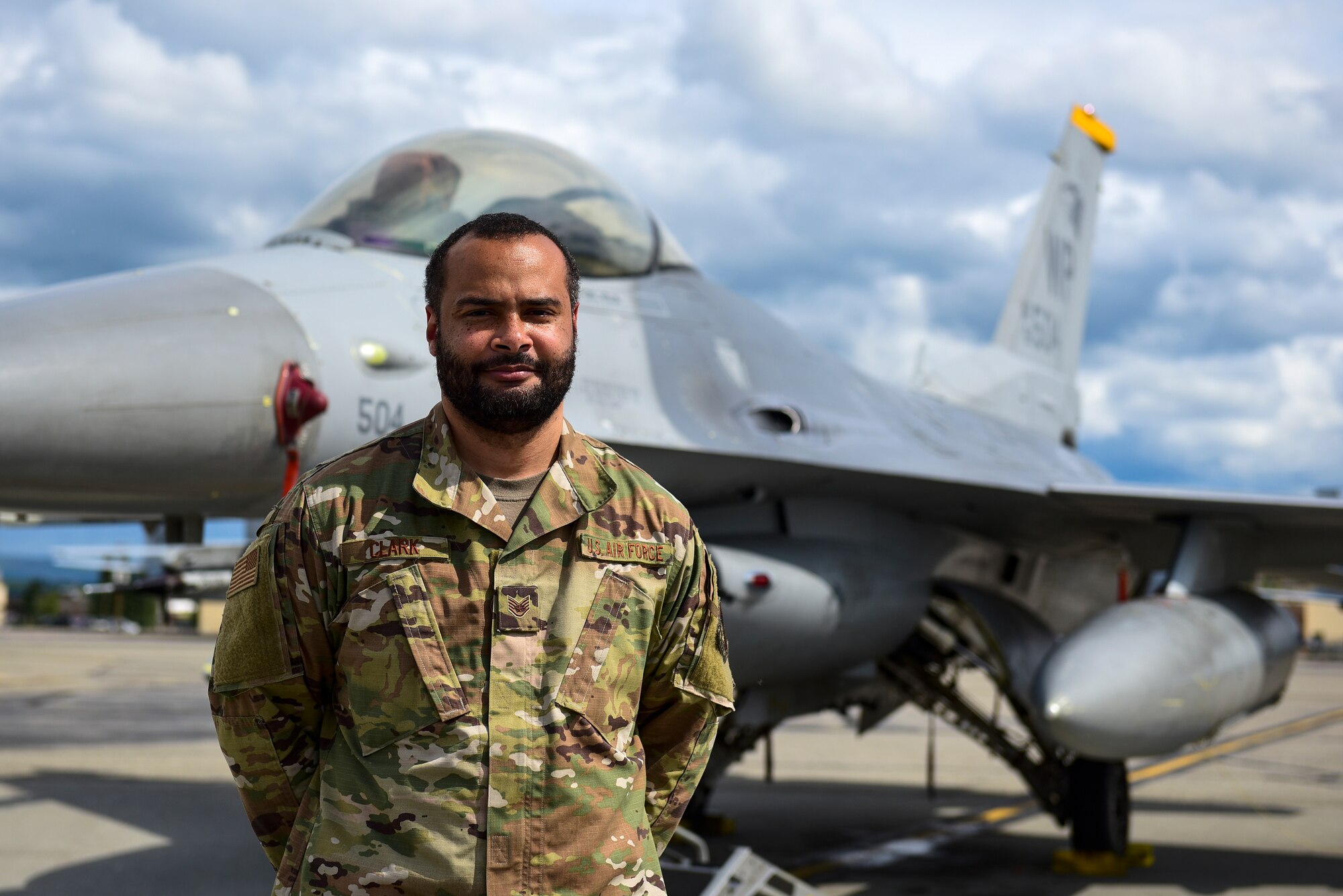 Staff Sgt. Joseph Clark, 80th Aircraft Maintenance Unit weapons load crew chief, poses in front of an F-16 Fighting Falcon at Eielson Air Force Base, June 22, 2021. Clark decided to join the military to provide a better life for his family and get away from Brooklyn, New York, to avoid criminal activity. He uses his experiences of when he first joined the military to promote a culture of being inclusive so everyone feels accepted. (U.S. Air Force photo by Senior Airman Suzie Plotnikov)