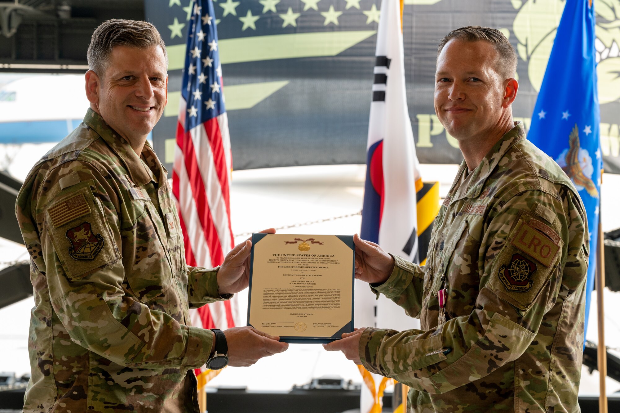 Col. Christopher Kiser, 515th Air Mobility Operations Group commander, left, presents Lt. Col. Ryan Murray, 731st Air Mobility Squadron outgoing commander, with the Meritorious Service Medal during the change of command ceremony at Osan Air Base, Republic of Korea, July 1, 2021. Edmunds earned the Meritorious Service Medal for his conduct as the 731st AMS commander.  (U.S. Air Force photo by Tech. Sgt. Nicholas Alder)