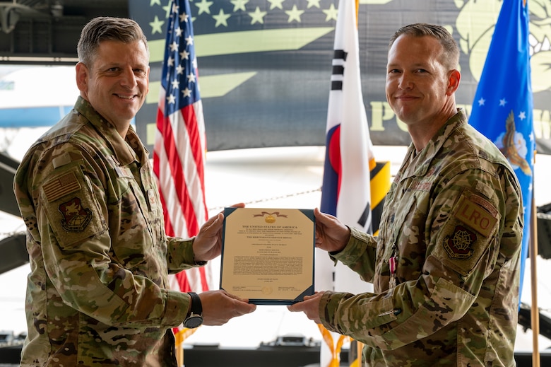Col. Christopher Kiser, 515th Air Mobility Operations Group commander, left, presents Lt. Col. Ryan Murray, 731st Air Mobility Squadron outgoing commander, with the Meritorious Service Medal during the change of command ceremony at Osan Air Base, Republic of Korea, July 1, 2021. Edmunds earned the Meritorious Service Medal for his conduct as the 731st AMS commander.  (U.S. Air Force photo by Tech. Sgt. Nicholas Alder)