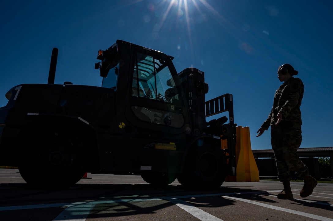 Senior Airman Brooke Hanson, 32nd Aerial Port Squadron cargo specialist, signals a fellow Airman driving a forklift to continue backing up during a training scenario at the Pittsburgh International Airport Air Reserve Station, Pennsylvania, June 16, 2021.