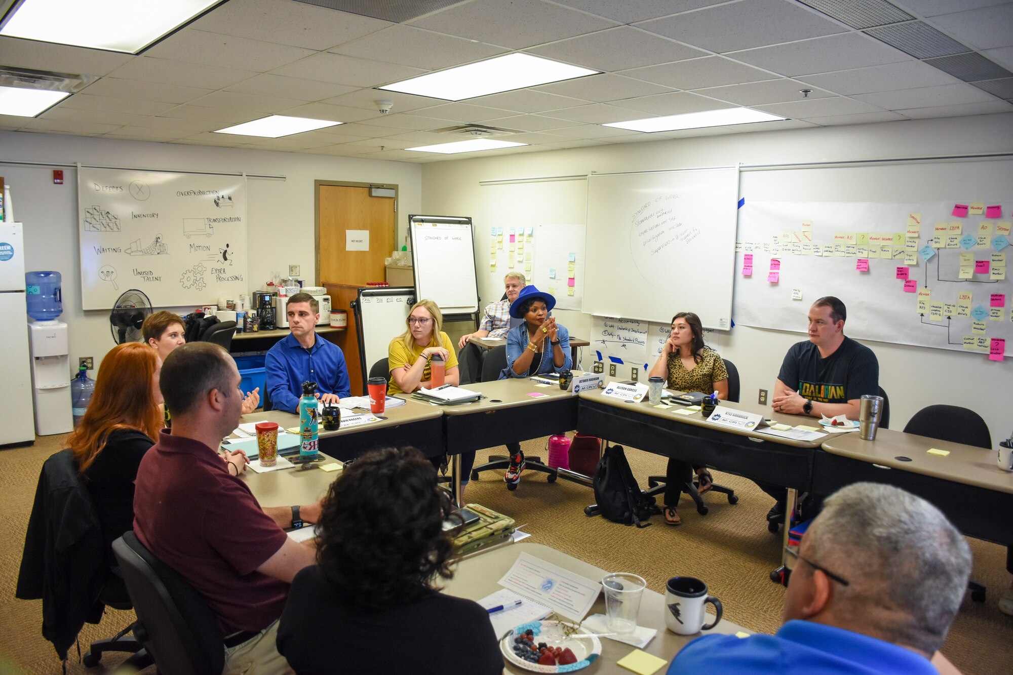 Eleven people sit around a U-shaped table, discussing the best course of action.