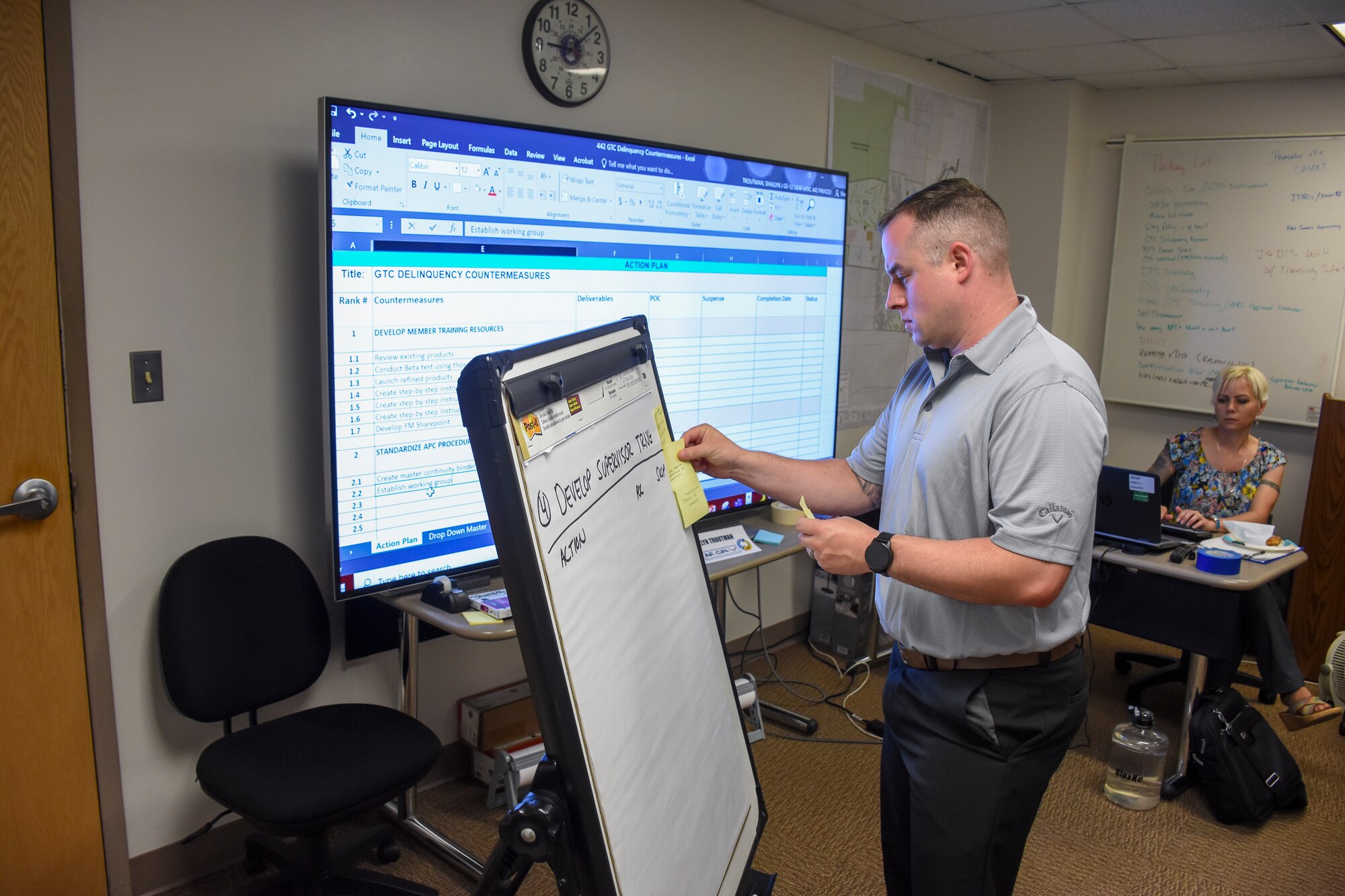 Tech. Sgt. Jeff Abel places a sticky note onto a giant note pad, recording an idea from one of the team members.