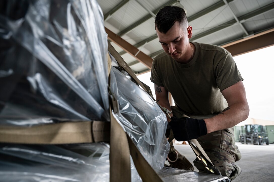 Staff Sgt. Tyler Roush, 32nd Aerial Port Squadron passenger service operations technician, tightens a cargo net on a pallet at the Pittsburgh International Airport Air Reserve Station, Pennsylvania, May 28, 2021.