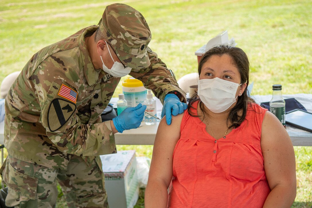 A soldier vaccinates a woman.