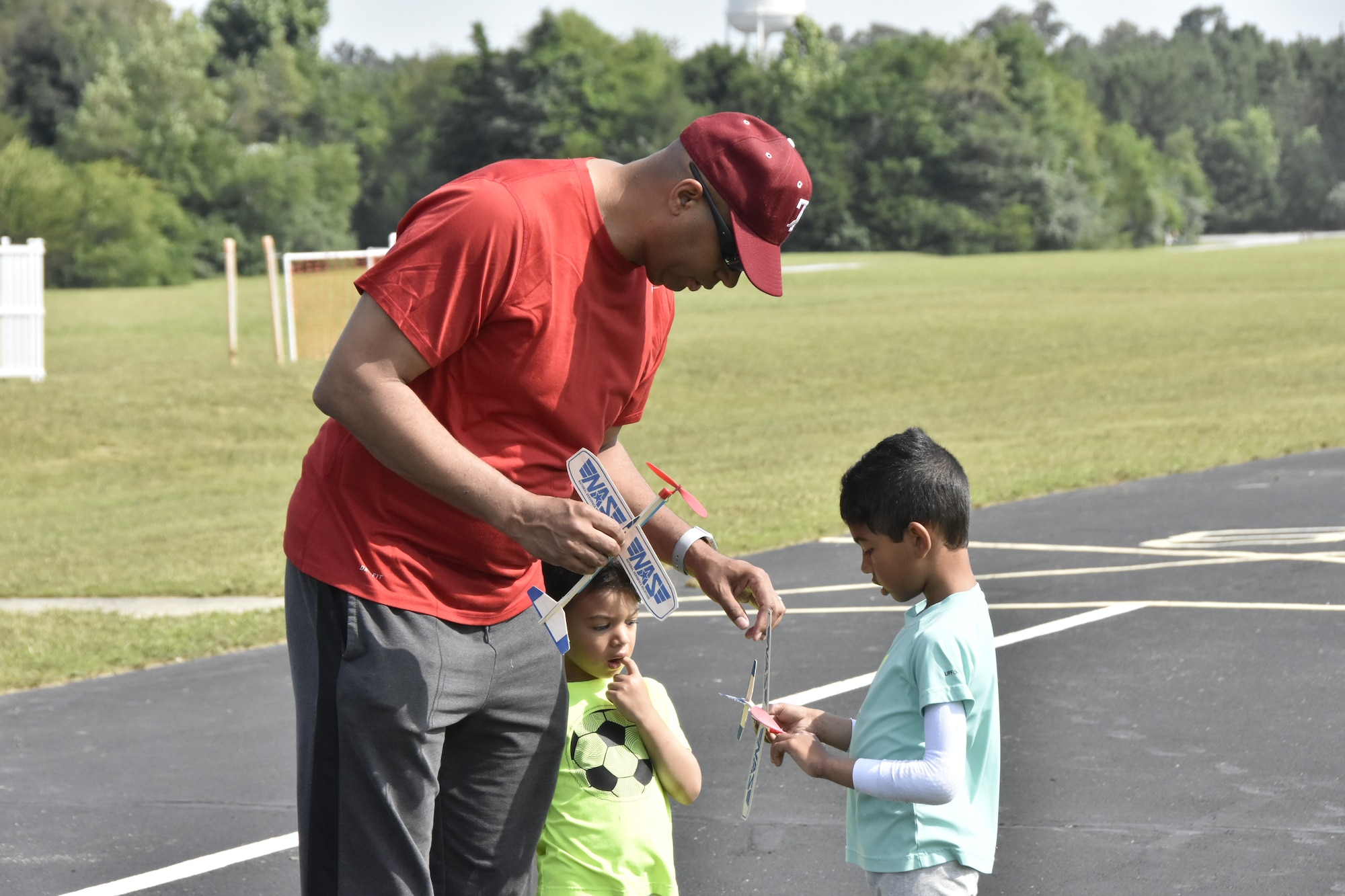 Col. Lincoln Bonner, chief of the Arnold Engineering Development Complex Test Division, helps his son Solomon, right, ready his balsa wood airplane for a practice toss during a June 26, 2021, event hosted by the Coffee Airfoilers Model RC Club to coincide with the AEDC 70th anniversary celebration. Also pictured is Bonner’s son Romal. Youth participating in the event were tasked with assembling small balsa wood airplanes, with top prizes going to those whose planes flew the farthest from the launch line. The event was intended to promote science, technology, engineering and mathematics, or STEM, interest among students taking part. (U.S. Air Force photo by Bradley Hicks)