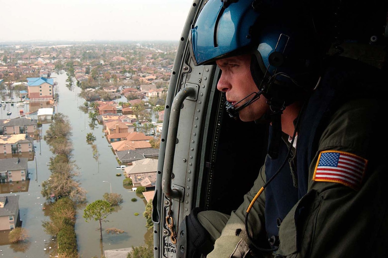 A person looks out of a helicopter at flooding.