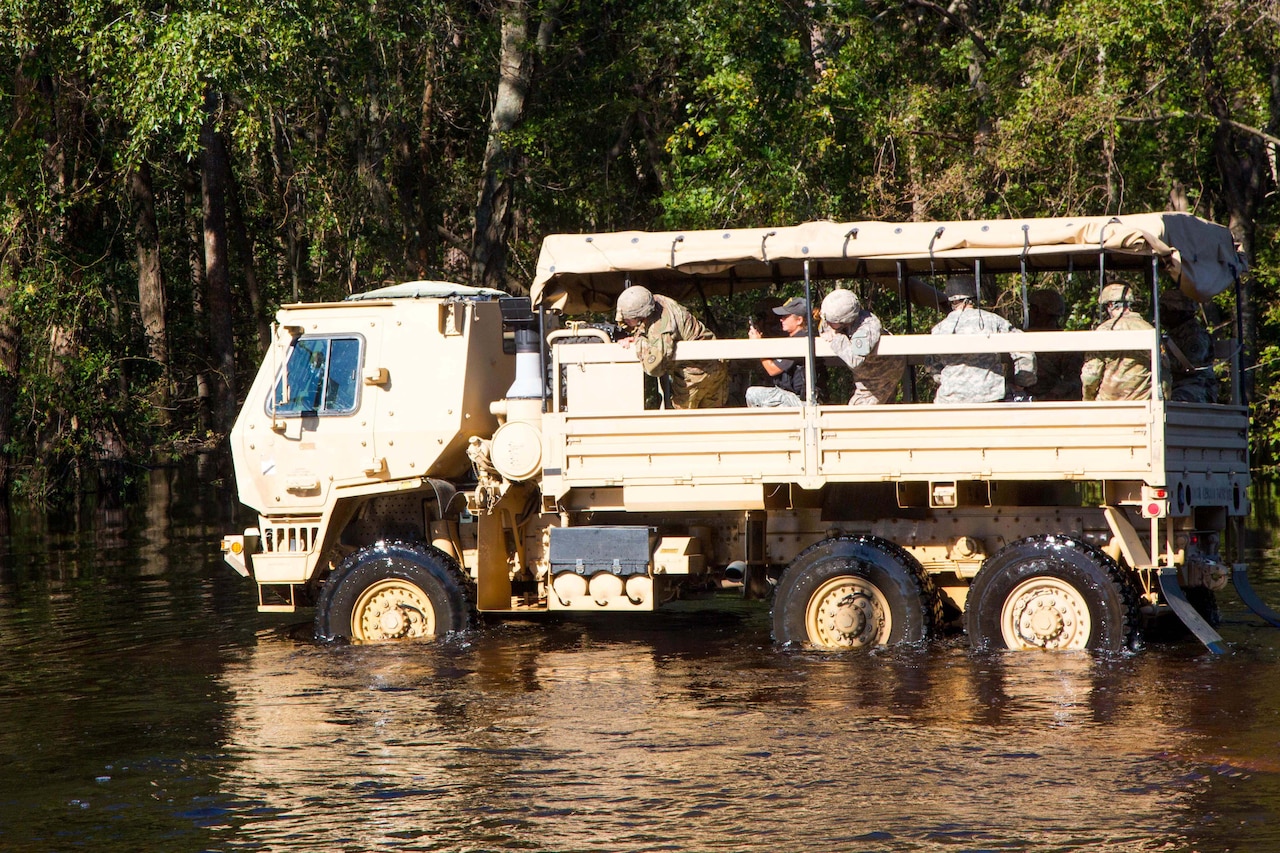 Troops ford a river in a truck.