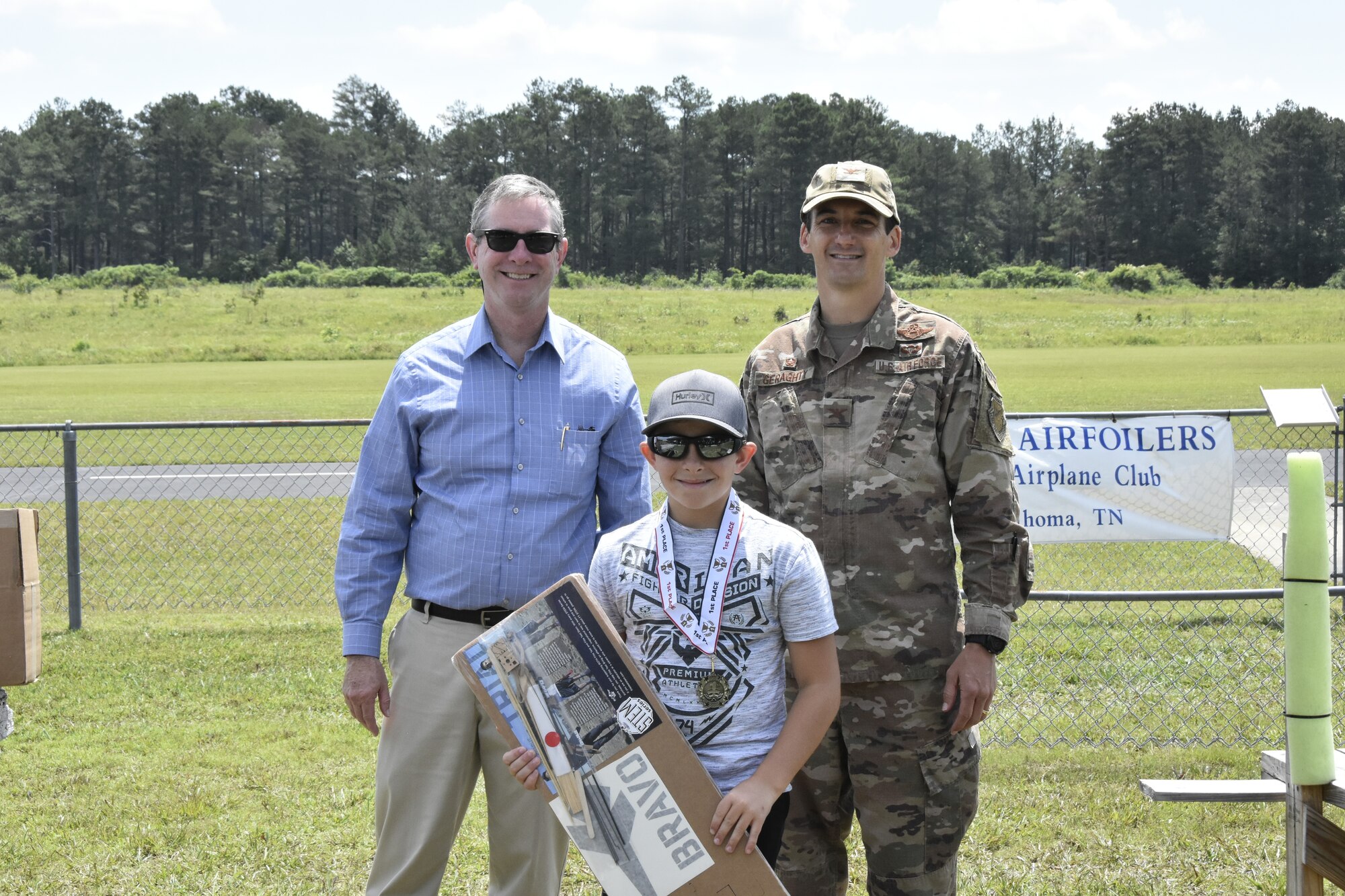 Bryce Spencer, center, was a first-place winner in the Coffee Airfoilers Model RC Club June 26, 2021, airplane toss competition hosted by the club to coincide with the Arnold Engineering Development Complex 70th anniversary. Also pictured are AEDC Commander Col. Jeffrey Geraghty, right, and AEDC Vice Director Jason Coker. Youth participating in the event were tasked with assembling small balsa wood airplanes, with prizes going to those whose planes flew the furthest from the launch line. The event was intended to promote science, technology, engineering and mathematics, or STEM, interest among students taking part. (U.S. Air Force photo by Bradley Hicks)