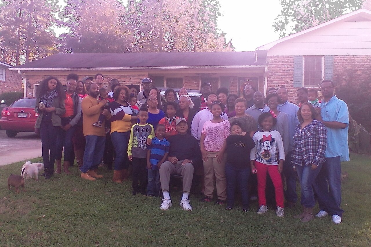 A large group of people pose for a photo in front of a house.