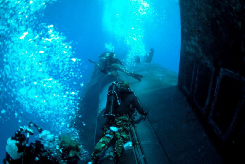 Navy SEALS navigate underwater.