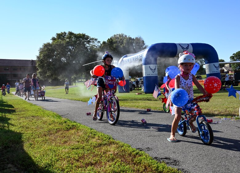 Airmen and their families participate in a patriotic bike parade