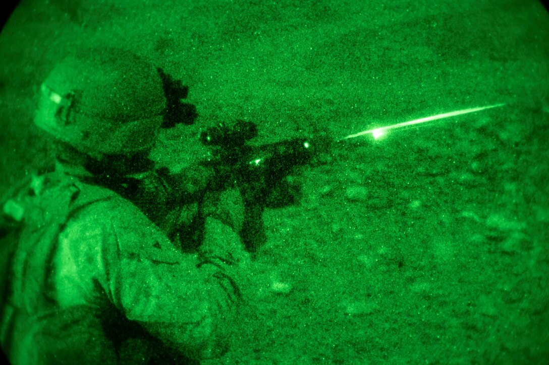 A Marine fires a weapon as seen through night vision googles.