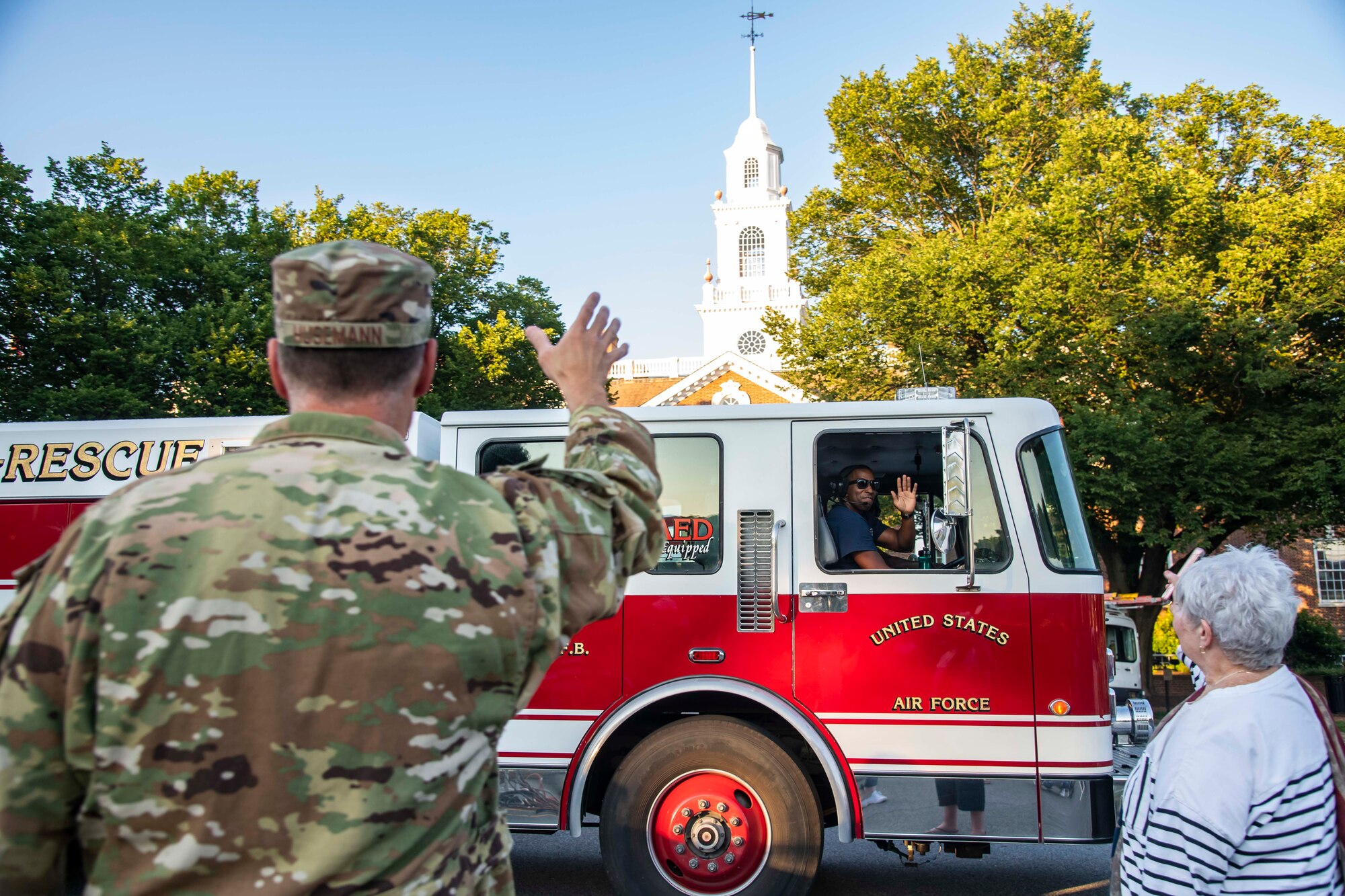A member of the 436th Civil Engineer Squadron fire department waves to Col. Matt Husemann, 436th Airlift Wing commander, and other members of the crowd during the annual Fourth of July Celebration parade in Dover, Delaware, July 4, 2021. The Dover Air Force Base Honor Guard also participated in the event.  (U.S. Air Force photo by Senior Airman Stephani Barge)