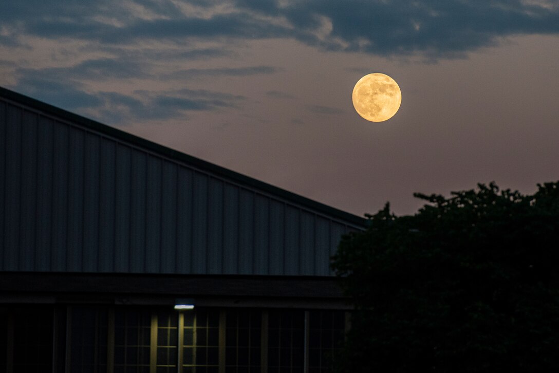 A nearly full moon lights up the sky over a building at Wright-Patterson Air Force Base, Ohio, June 23, 2021. The base has three fire stations strategically located to ensure a response time of 5 minutes or less when the call comes in. (U.S. Air Force photo by Wesley Farnsworth)