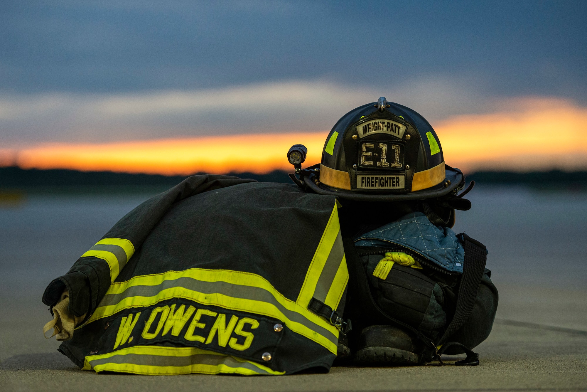 Bunker gear sits staged just outside the bays of Fire Station 1 for a sunset photo, June 23, 2021 at Wright-Patterson Air Force Base, Ohio.  The base has three stations strategically located to ensure a response time of 5 minutes or less when the call comes in. (U.S. Air Force photo by Wesley Farnsworth)