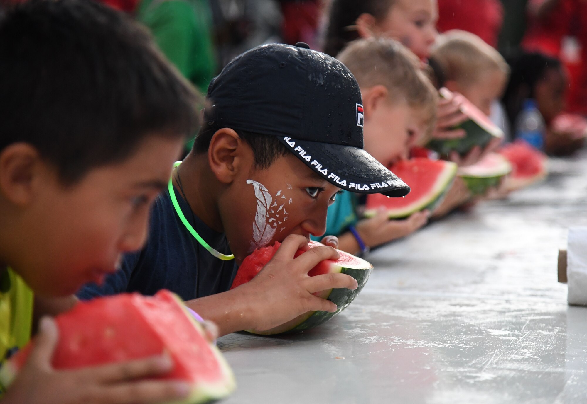 Katavion Brown, son of U.S. Navy Culinary Specialist Kevin Brown, Naval Construction Battalion Center Gulfport senior chief, participates in a watermelon eating contest during Freedom Fest at Marina Park at Keesler Air Force Base, Mississippi, July 2, 2021. The event also included hot dogs and wings eating competitions and fireworks. (U.S. Air Force photo by Kemberly Groue)