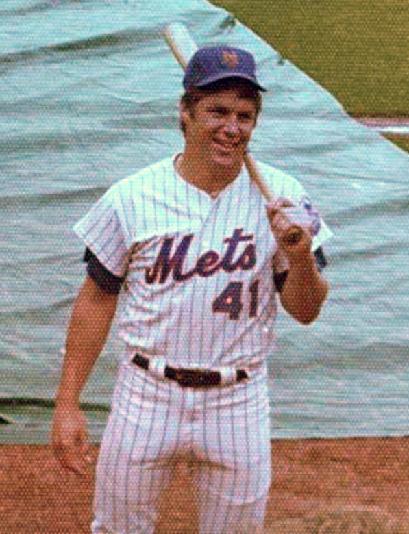 A baseball player holds a bat on his shoulder.
