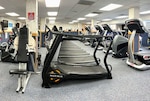 fitness room filled with functional fitness equipment like a squat rack, weight plates, flat benches, dumbbells and floor mats.