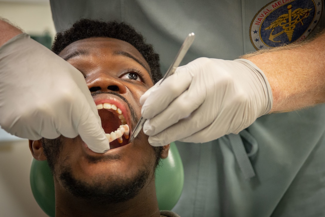 A dentist puts the bottom row of 3D teeth into the mouth of a patient.