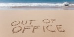 The words "Out of Office" written into a sandy beach