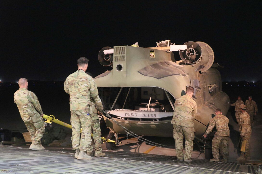 Troops load a helicopter onto an aircraft.